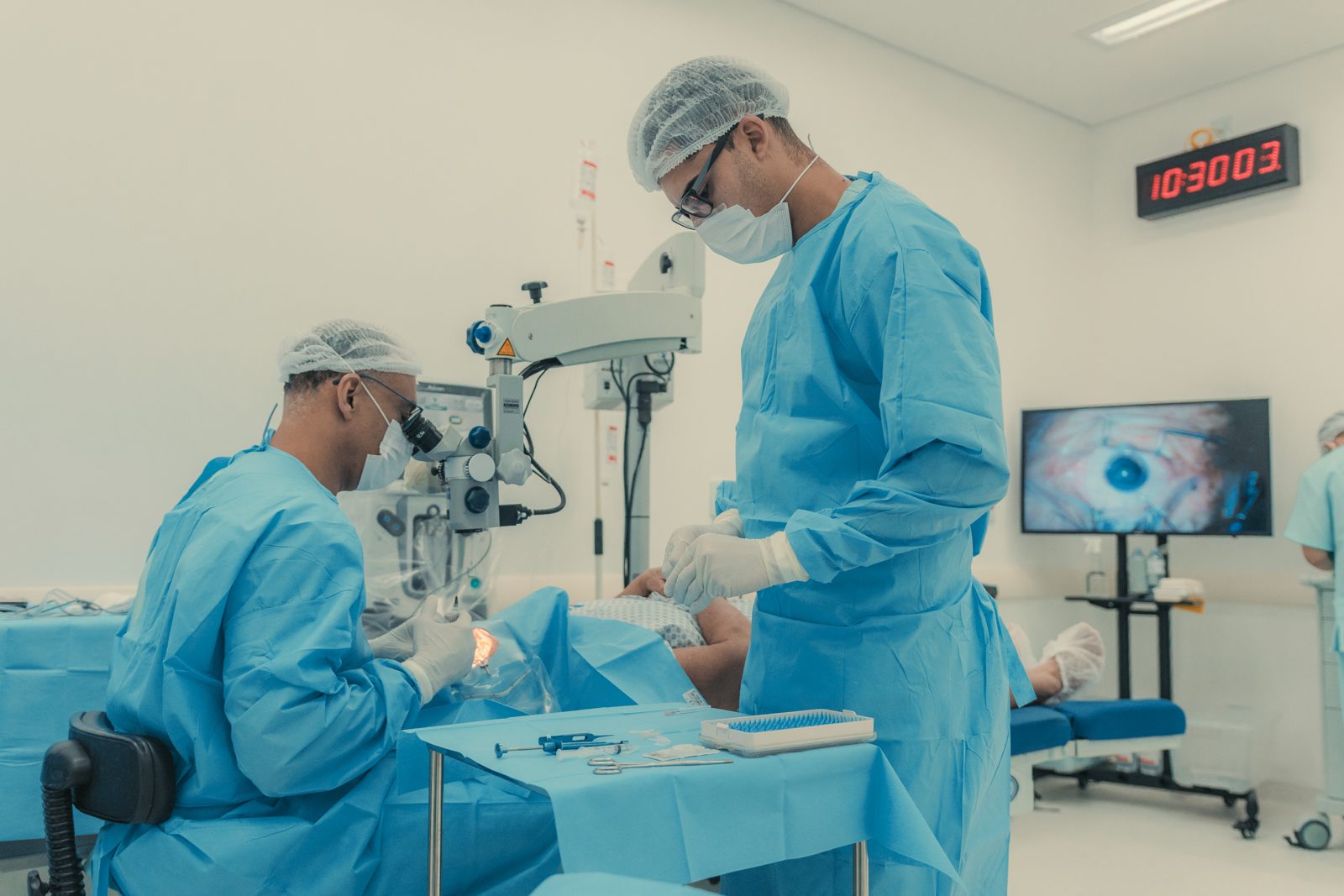 Cirurgia oftalmológica: médico no microscópio e o olho do paciente no monitor