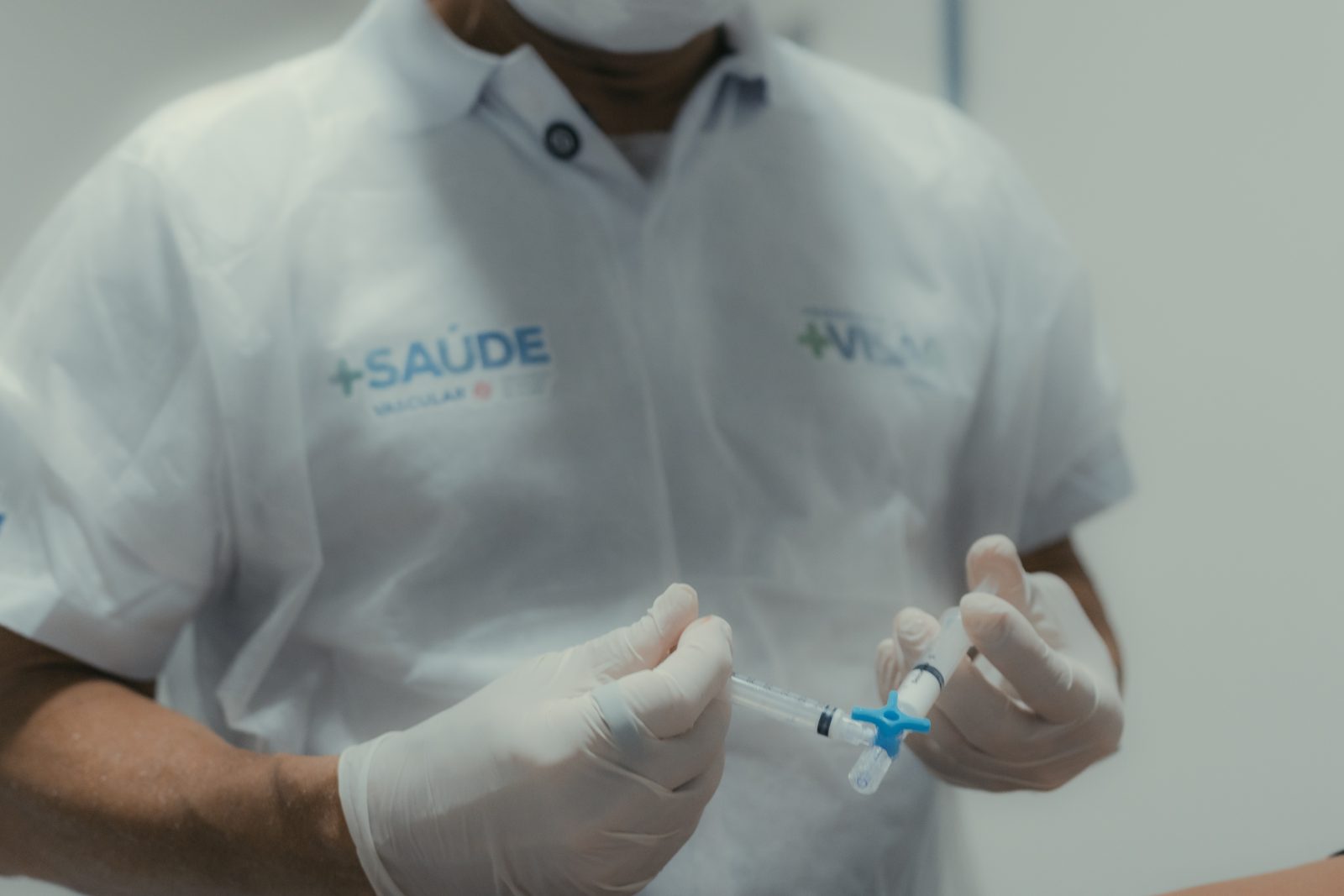 Profissional do +Saúde Vascular preparando um cateter com luvas cirúrgicas